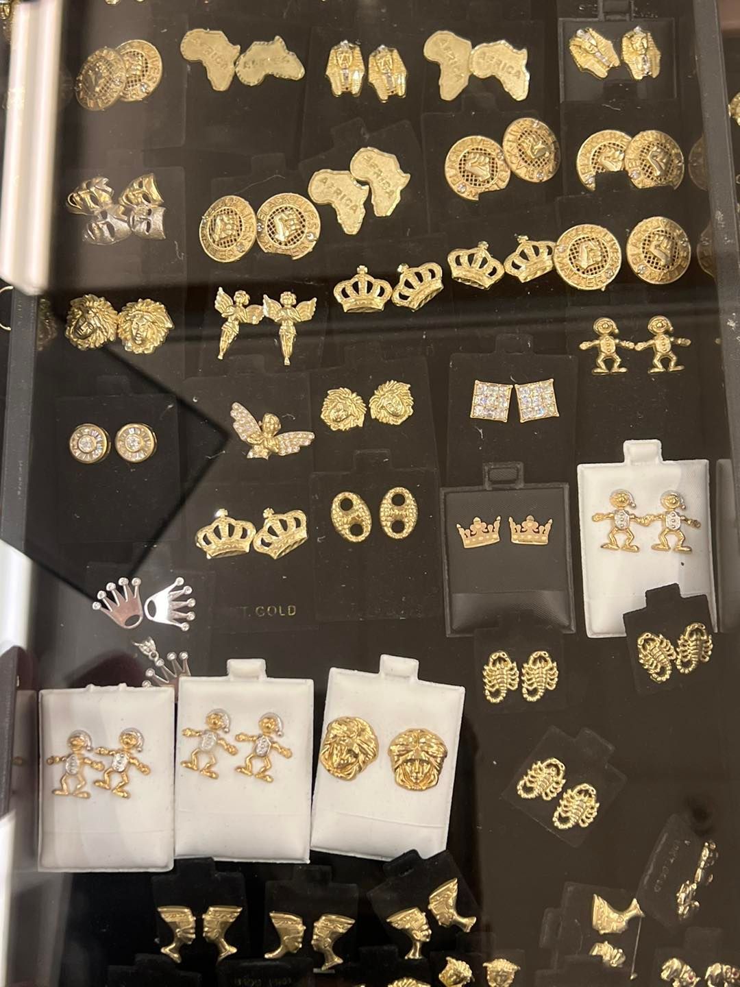 Gold earrings in various shapes and sizes displayed in a glass case.