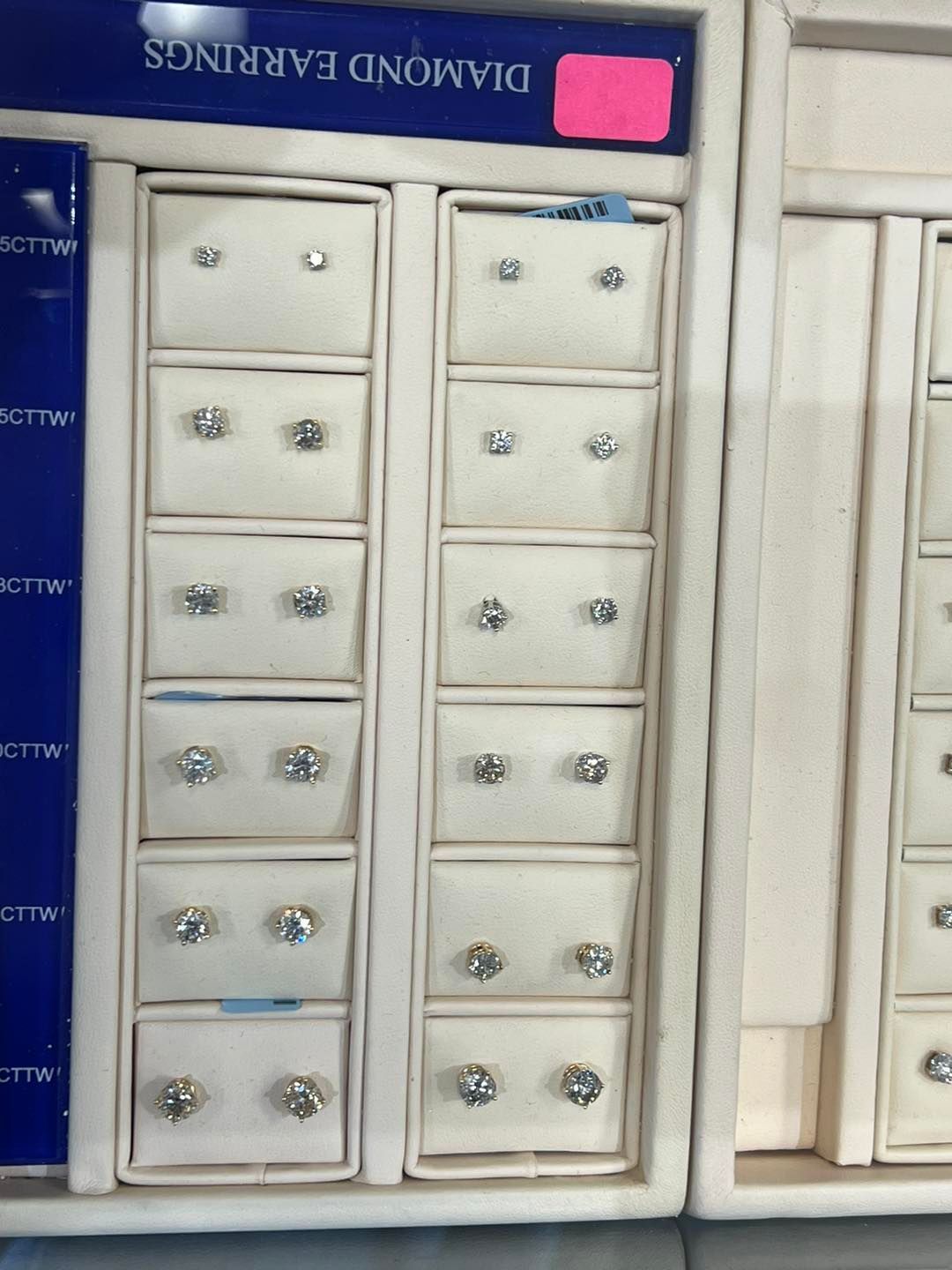 Diamond stud earrings displayed in a jewelry store case.