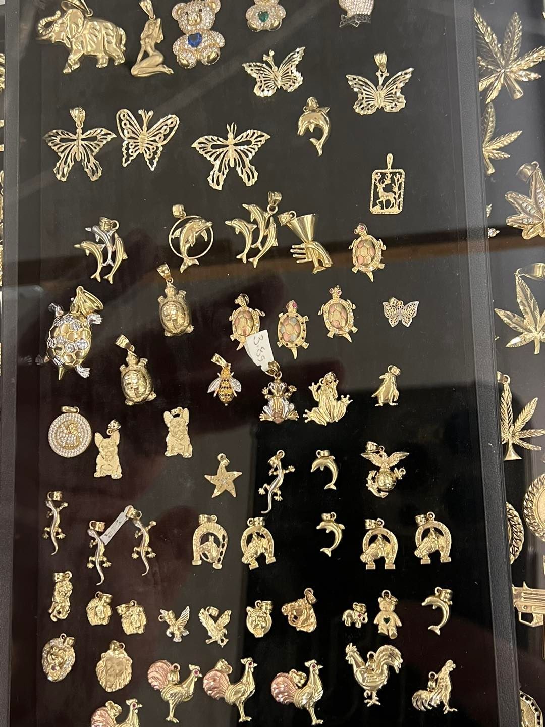 Gold jewelry charms in various animal and object shapes on a black display.