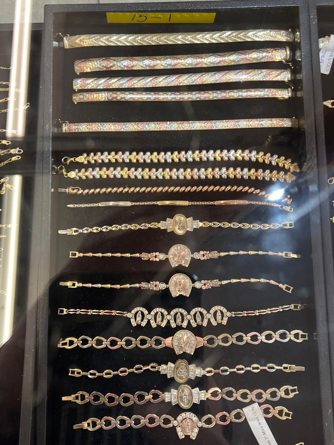 Display case of gold bracelets, various designs including chain, embellished, and decorative styles.
