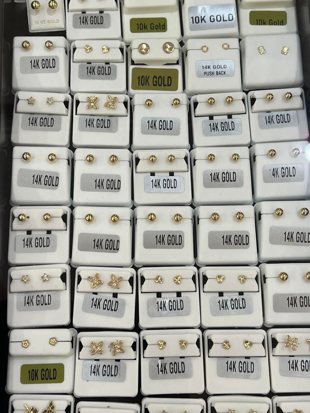 Rows of earring displays in white boxes, labeled with