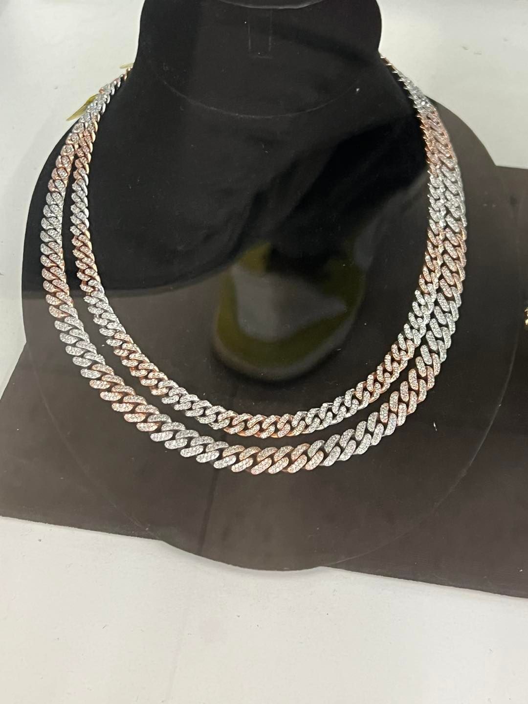 Two silver and rose gold chain necklaces displayed on a black mannequin bust.