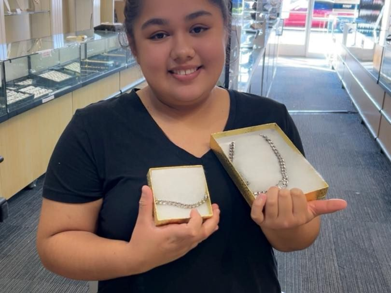 Woman in jewelry store holds boxes with jewelry; smiling in Fayetteville, NC.