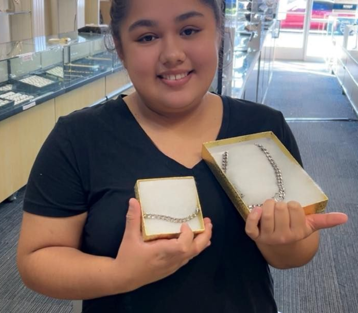Woman in jewelry store holds boxes with jewelry; smiling near Hope Mills, NC.