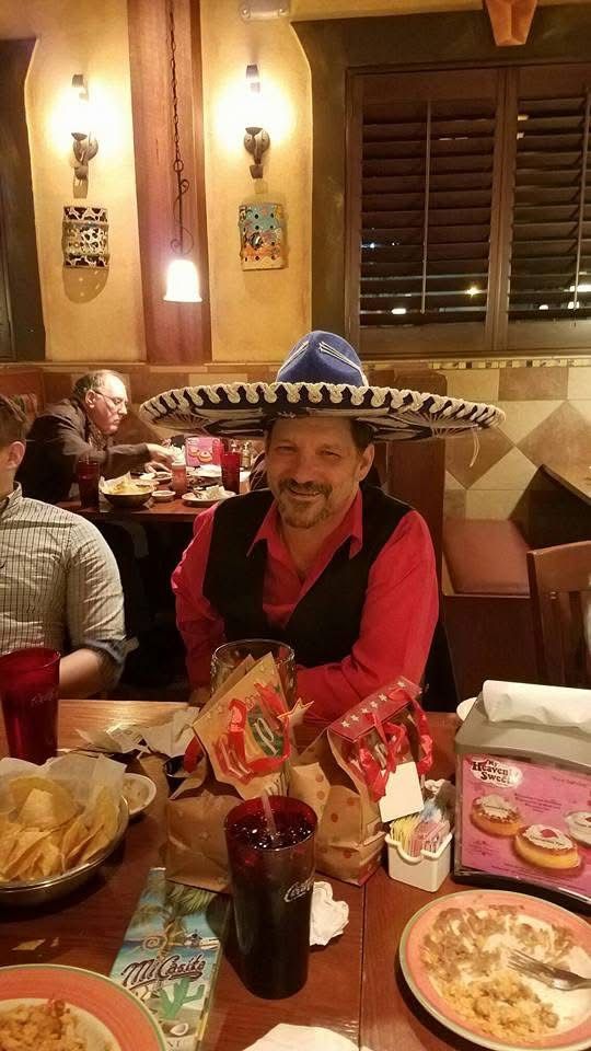 Man wearing a sombrero, seated at a restaurant table with food and drinks.