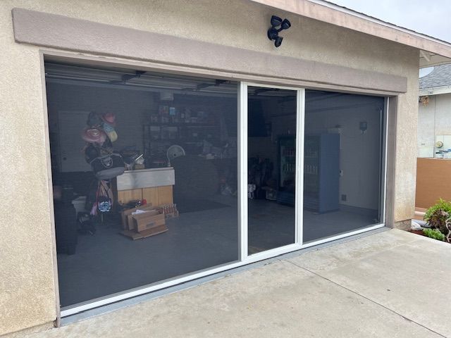 A worker installs hurricane shutters on a home's exterior wall.