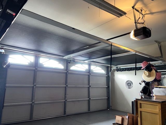 Two gray industrial roll-up doors with black and yellow bollards in front.