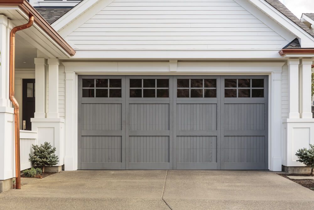 Gray garage door with windows in a white house.