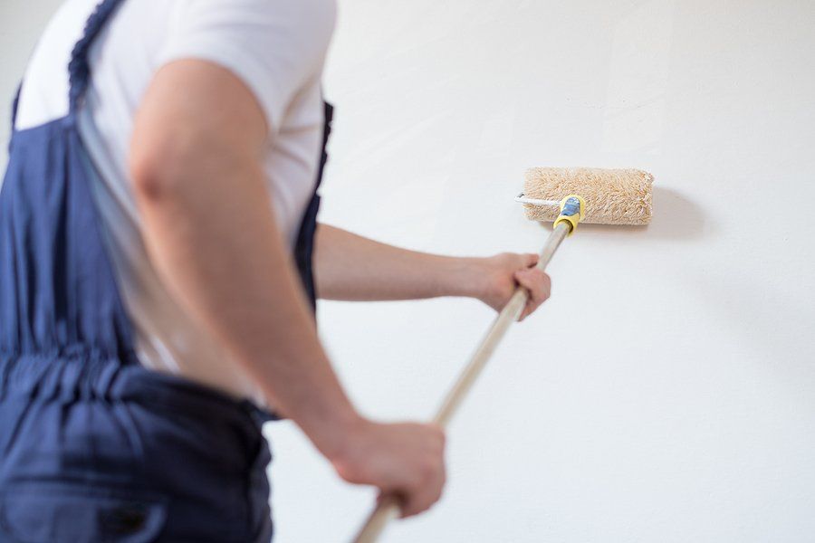 man painting the wall using a roller paint