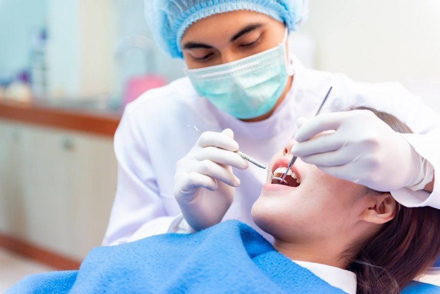 A Dentist is Examining a Woman 's Teeth in a Dental Office — ProCare Dental Australia in East Maitland, NSW
