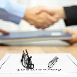 Shaking hands and exchanging folder— Attorney Services in Mineola, NY