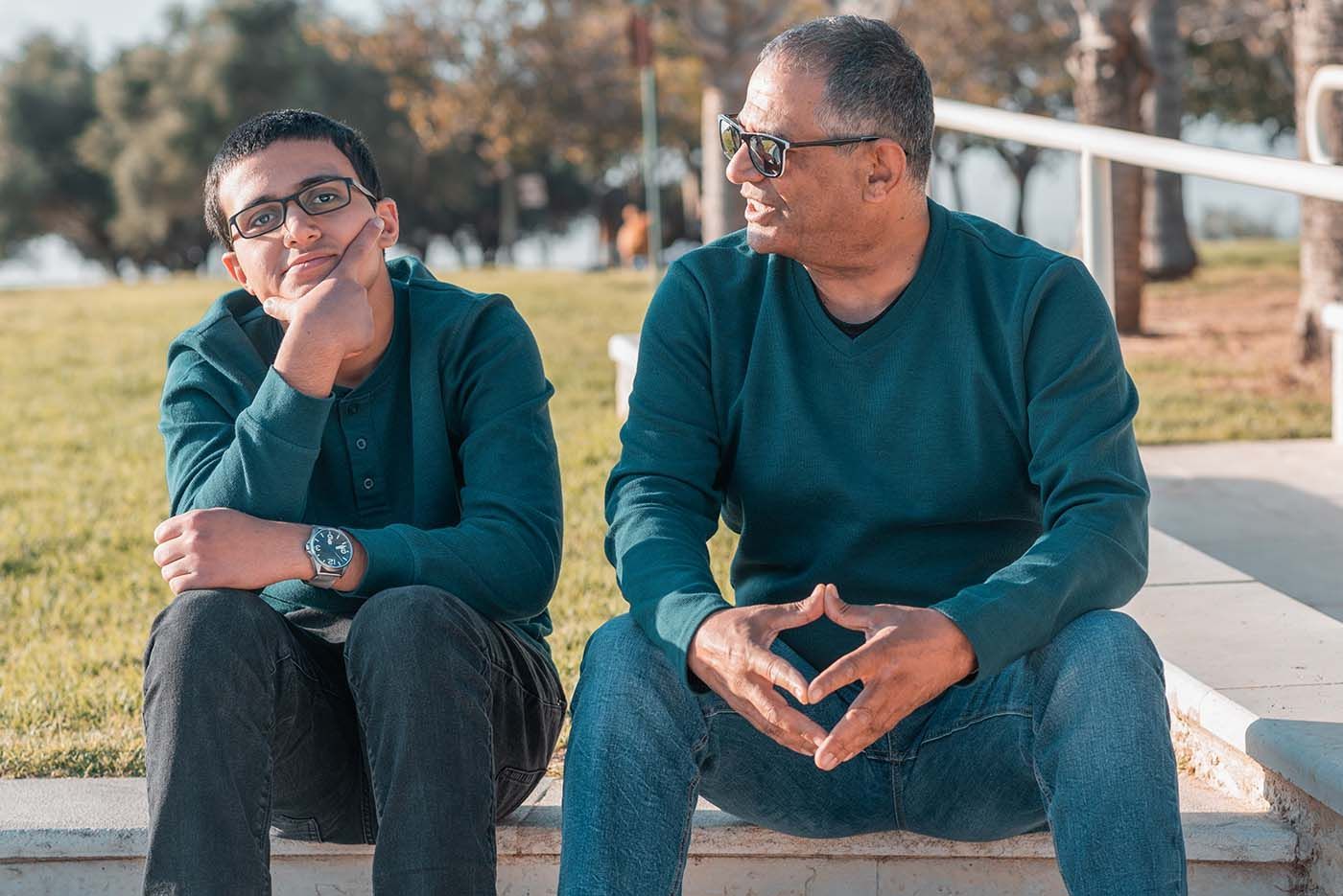 Stepfather sitting with his stepson in park. Learn about stepparent rights in New York.