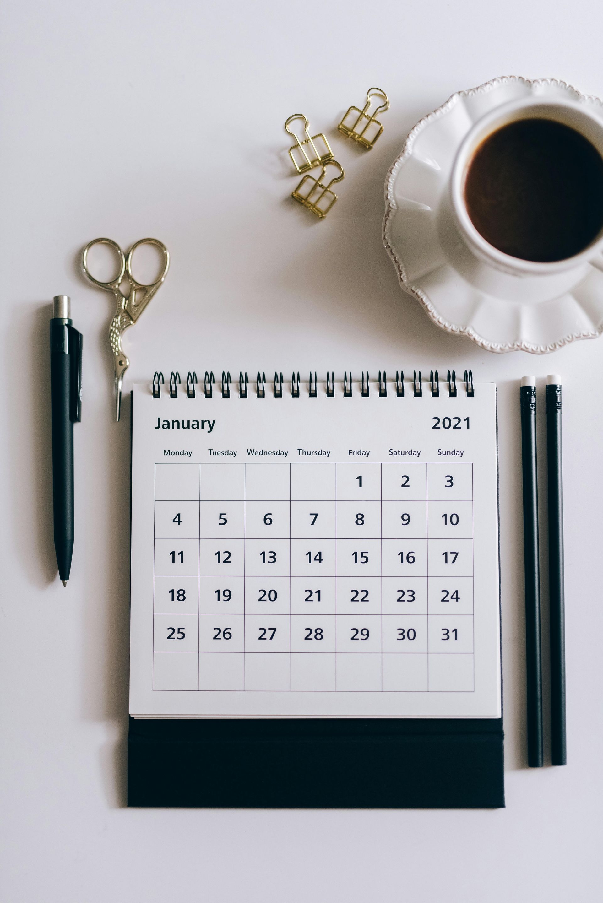 A calendar is sitting on a table next to a cup of coffee.