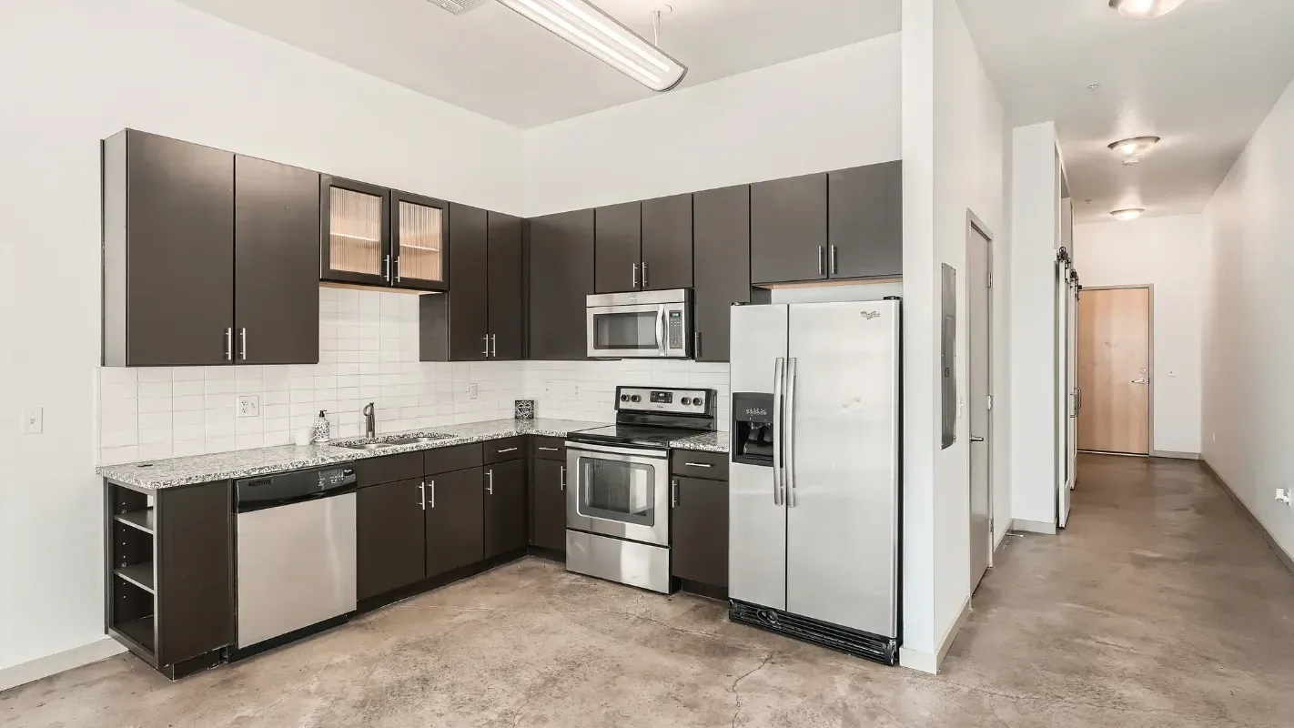 Kitchen in an apartment with dark cabinets, granite counters, and stainless steel appliances.