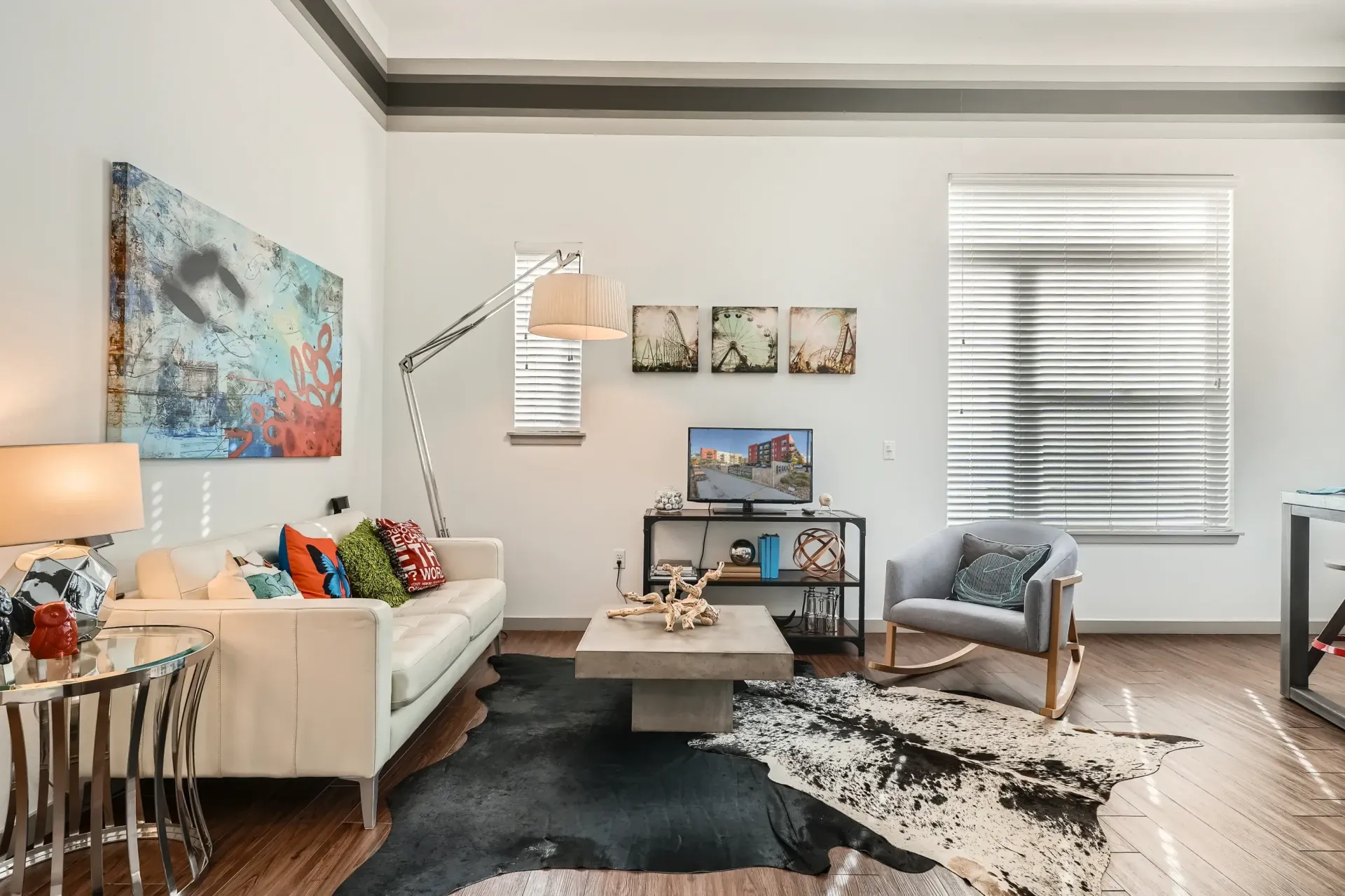 Bright modern apartment living room with white sofa, gray chair, coffee table, and wall art.