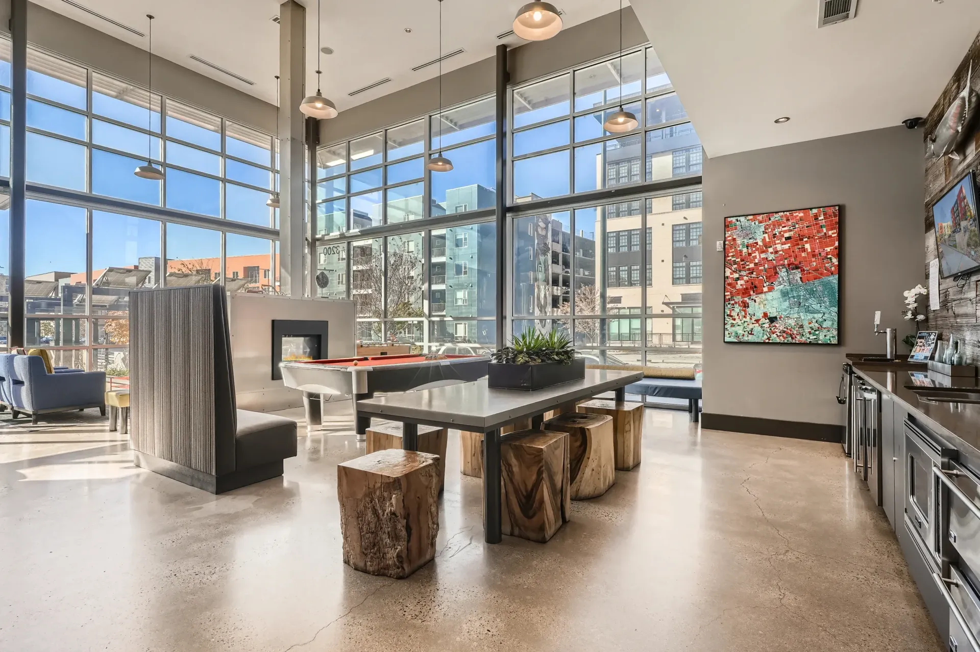 Bright community amenity lounge with large windows, pool table, and kitchenette.