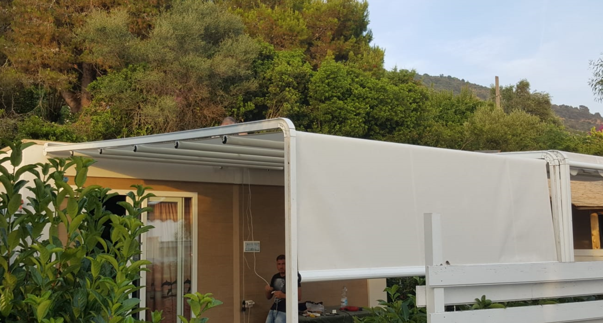 Un uomo è in piedi sotto una tettoia bianca davanti a una casa.