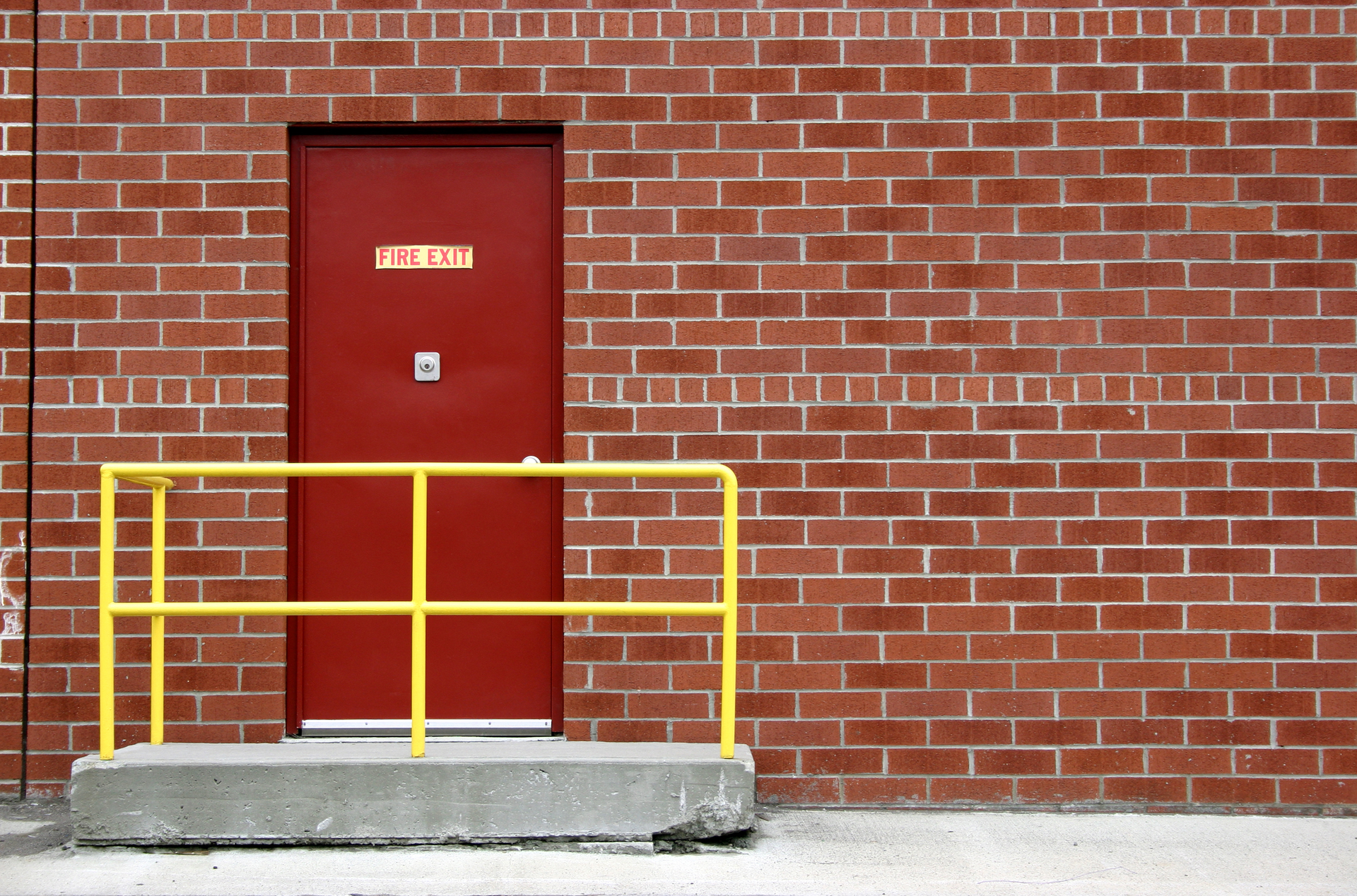 A fire exit door with a brick wall.