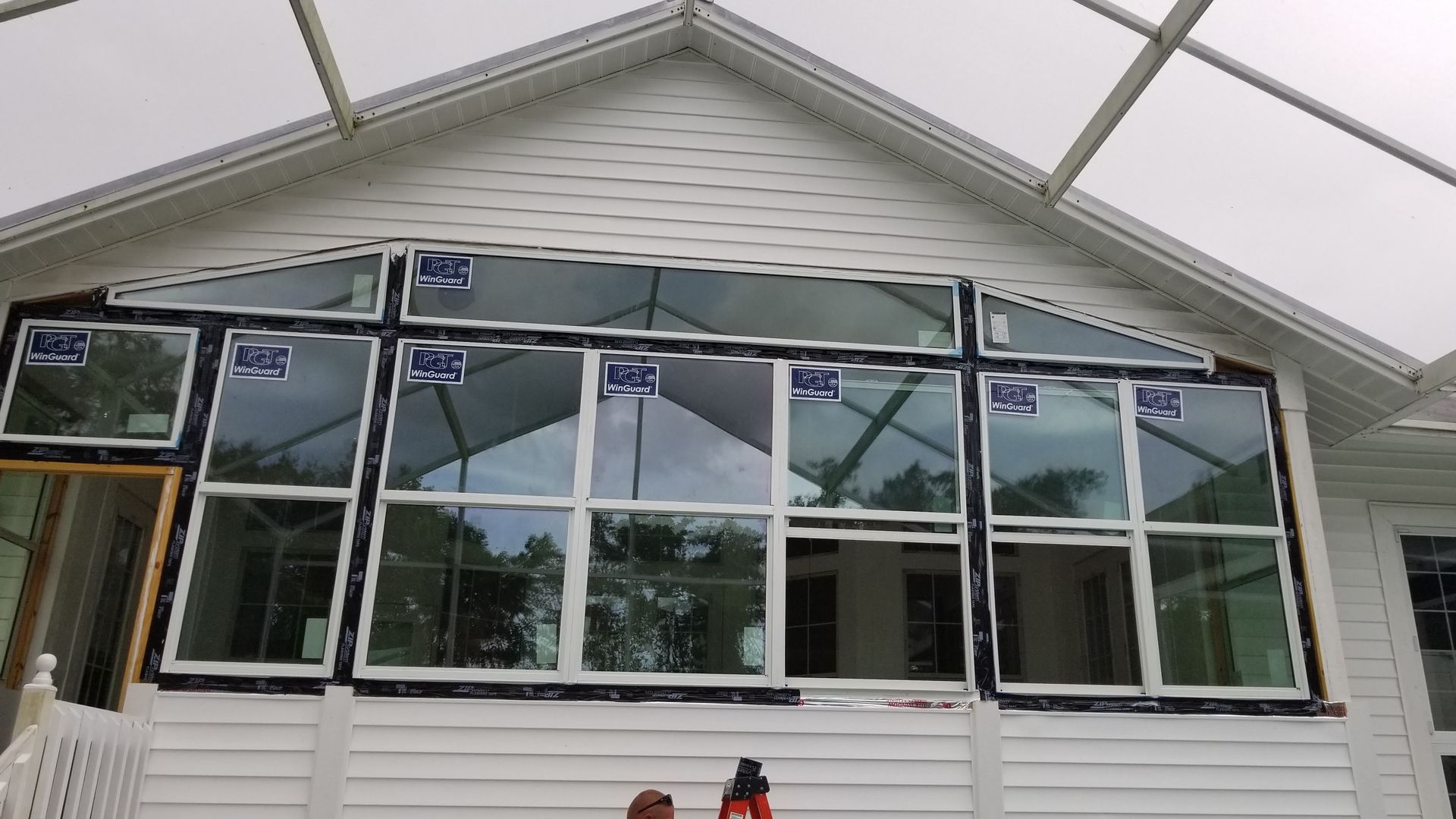 New windows installed on a white house with dark flashing; a few windows are still being installed.