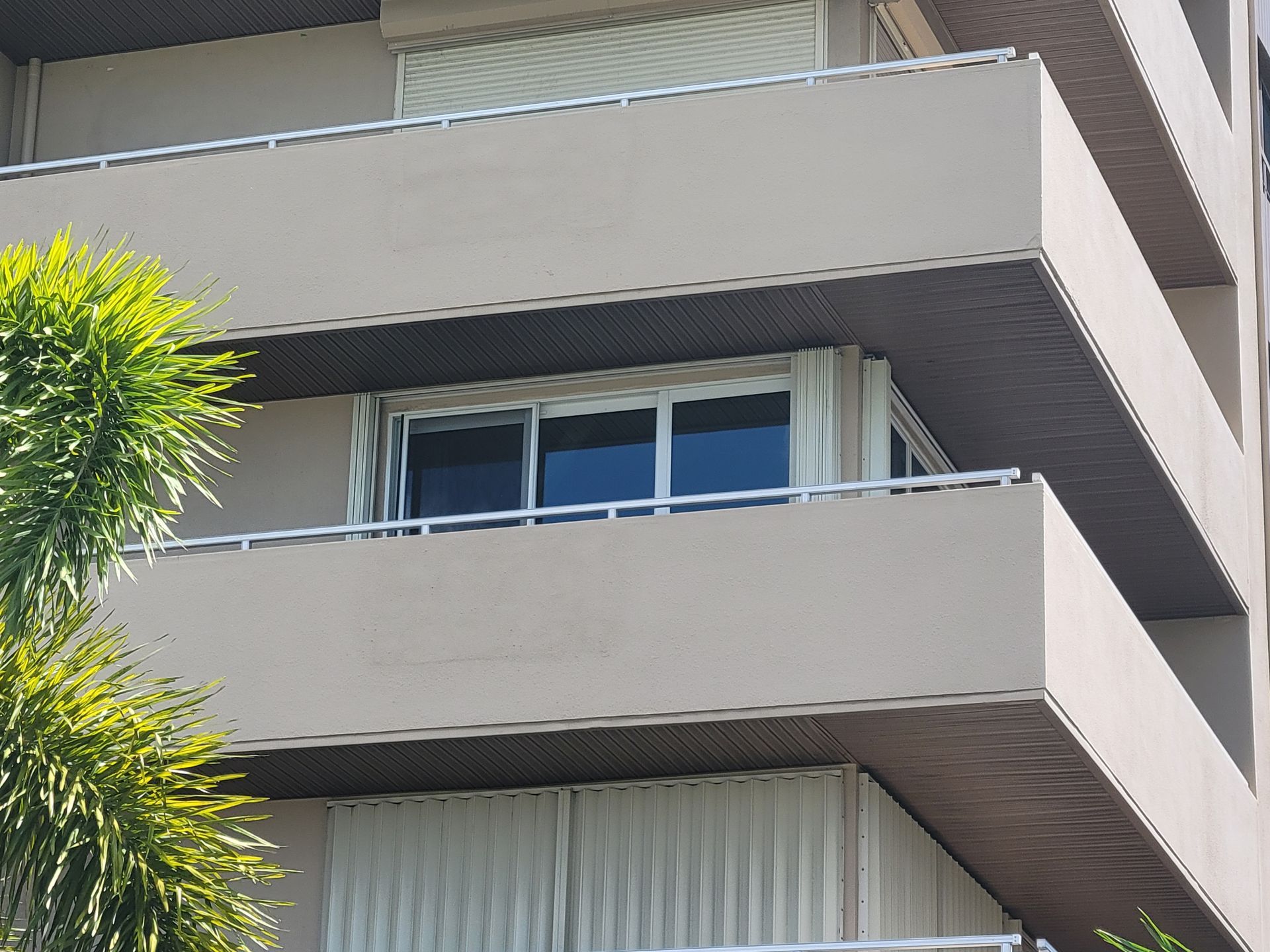 Multi-story building with balconies, beige walls, and closed blinds.