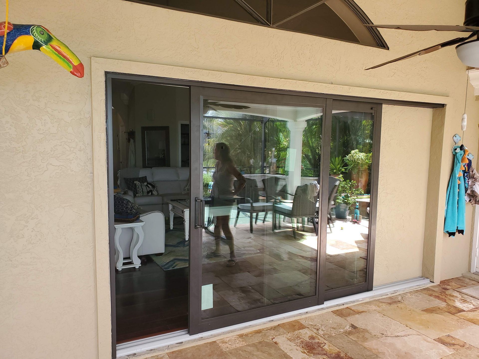 Sliding glass doors on a stucco building open to a patio, with a woman visible inside the house.