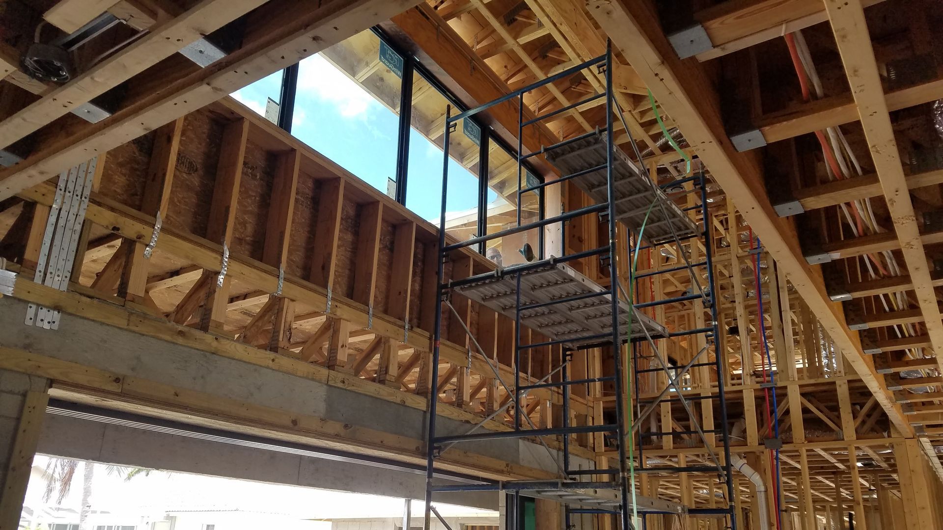 Construction site interior with wooden framework, scaffolding, and a large window.