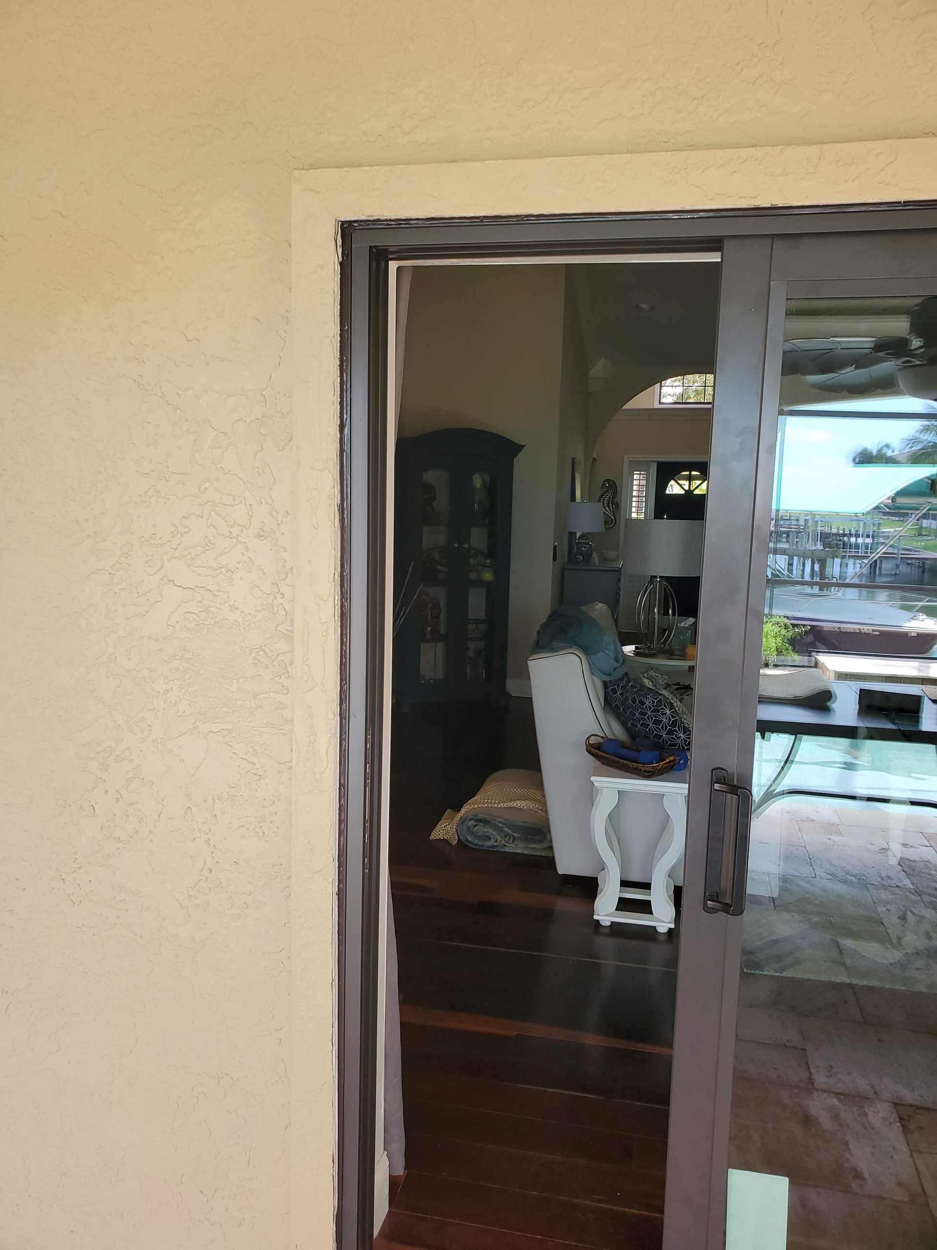 Sliding glass door, view into a living room, with a dark brown frame and wooden floors.