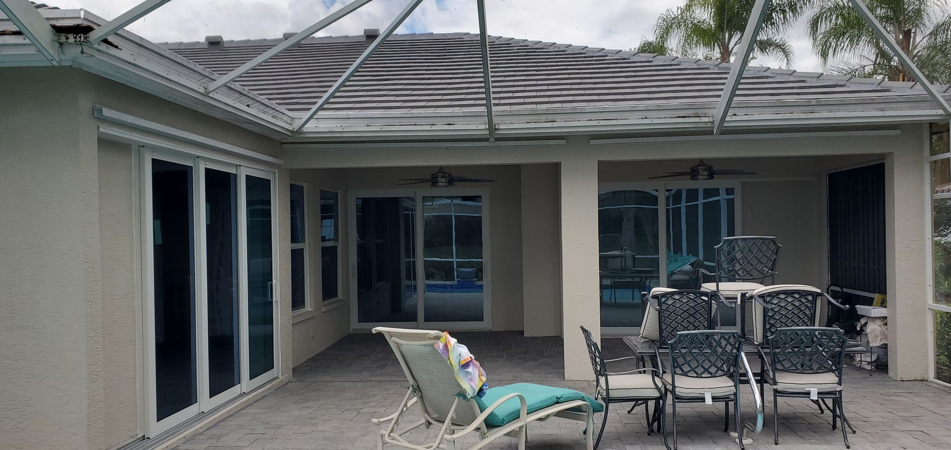Patio with gray roof, sliding glass doors, chairs, and a pool visible.