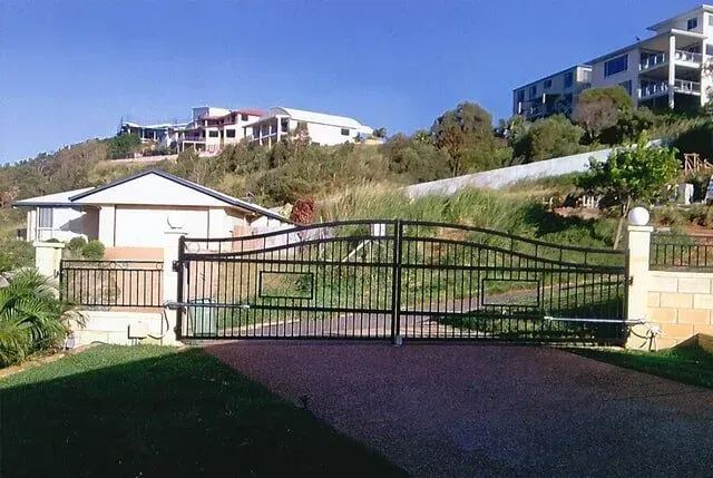 A Gated Driveway Leading To A House On A Hill — Rockhampton Powdercoating & Fence Panels in Park Avenue, QLD