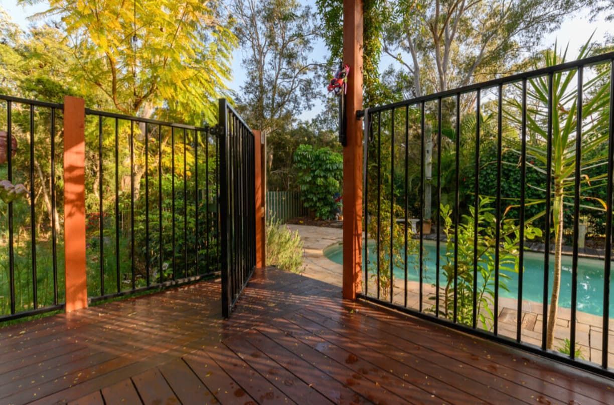 A Wooden Deck With A Metal Fence And A Pool In The Background — Rockhampton Powdercoating & Fence Panels in Park Avenue, QLD