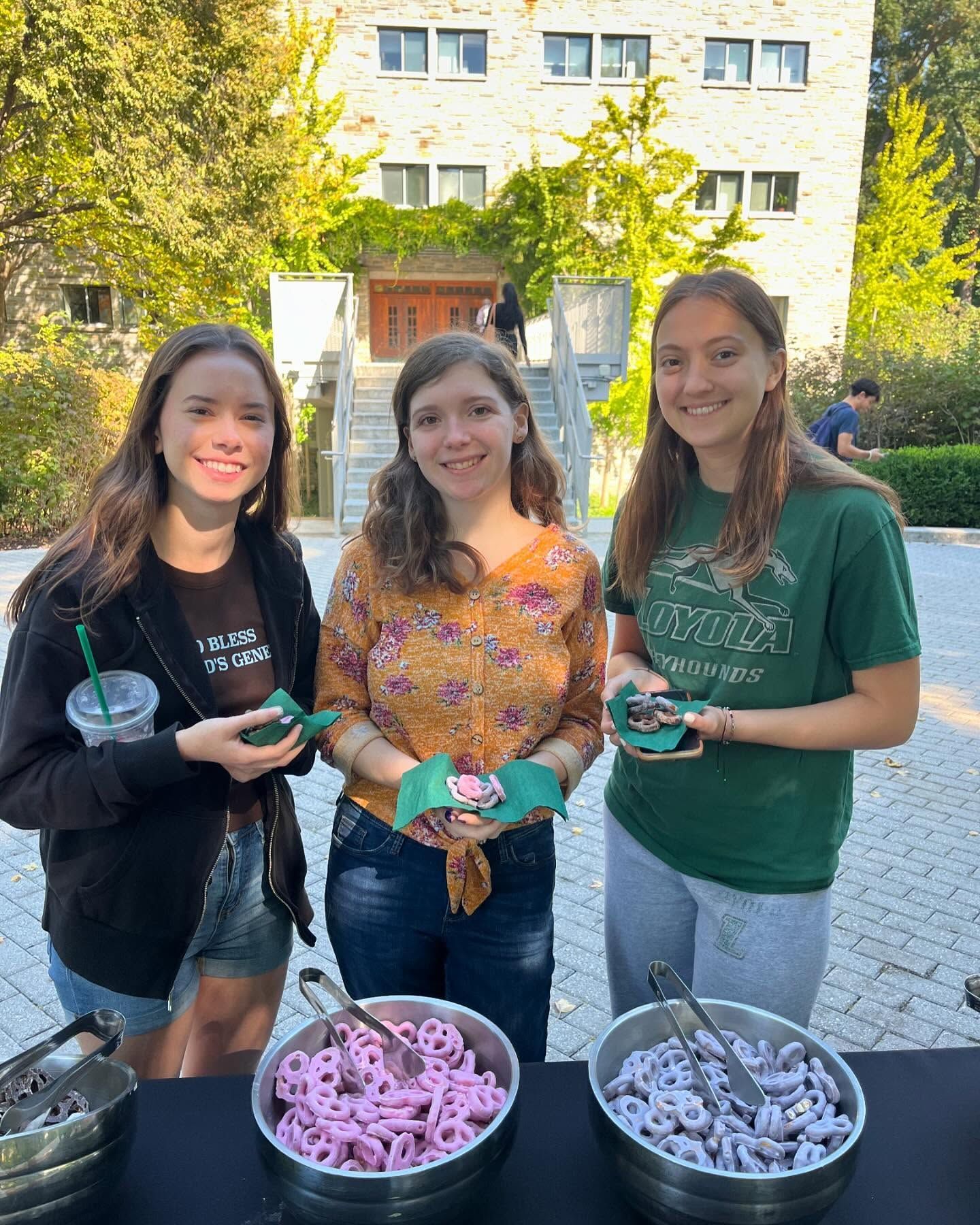 Three young women are standing next to each other holding bowls of food.