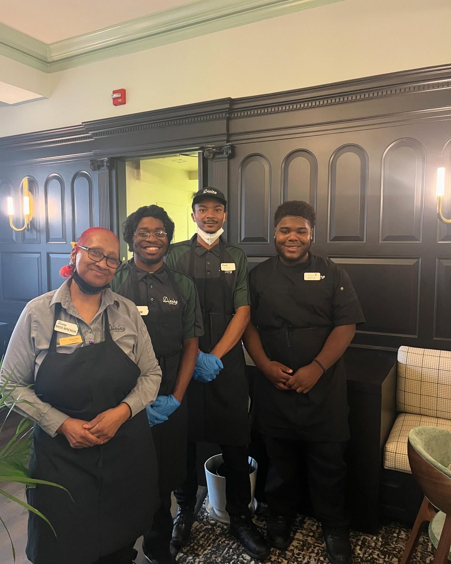 A group of people wearing aprons and gloves are posing for a picture.