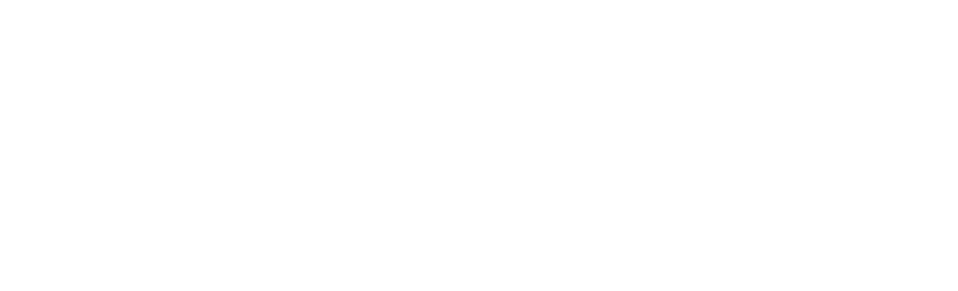 A young person stands in a kitchen, smiling while stirring ingredients in a large metal bowl on the counter.