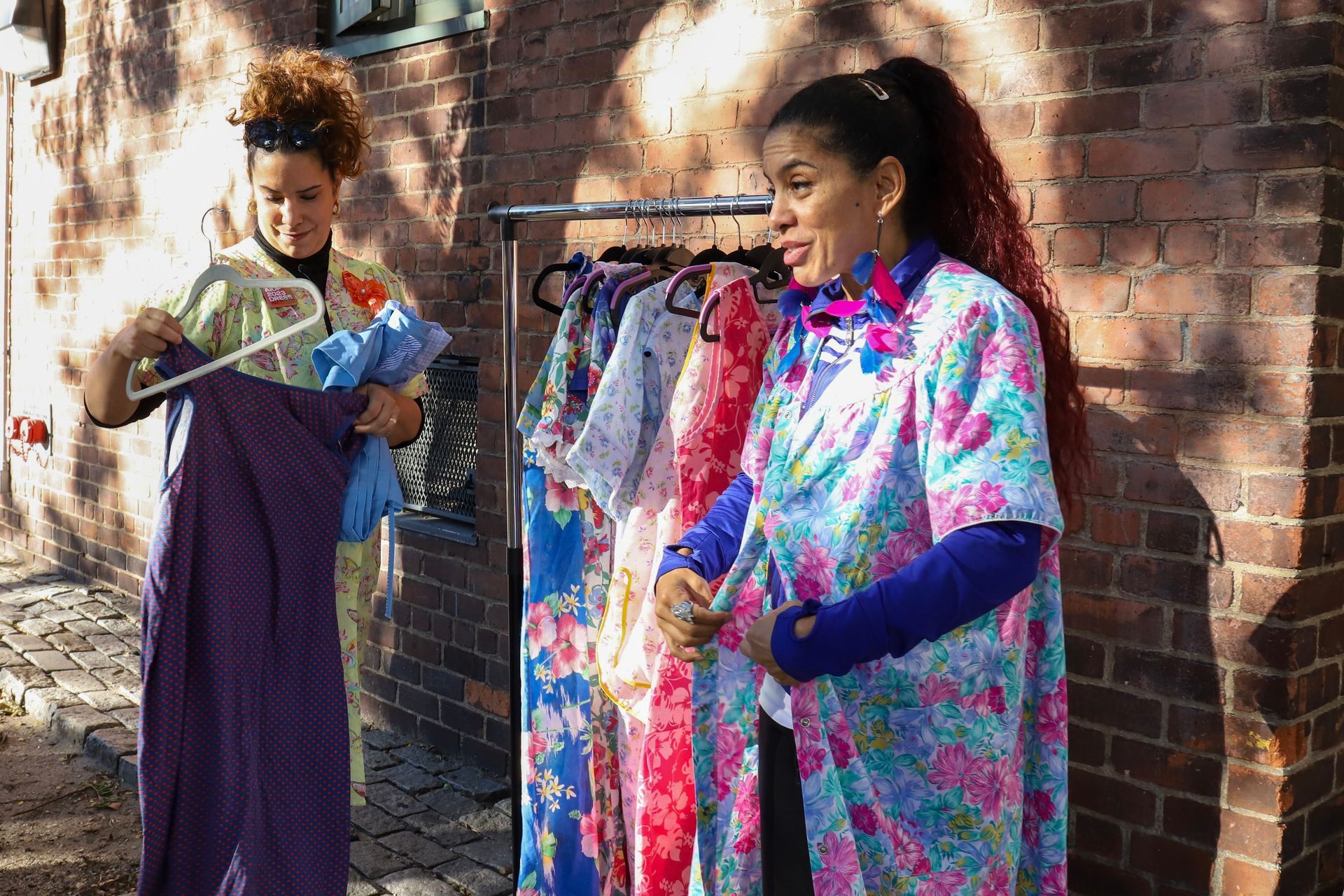 two women are standing next to each other looking at clothes on a rack .