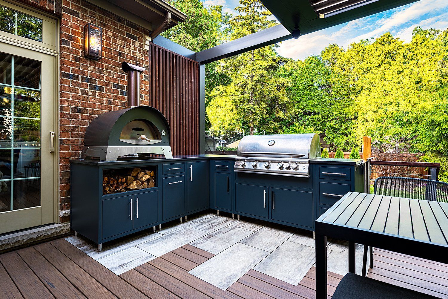 A large outdoor kitchen with a grill and a pizza oven.