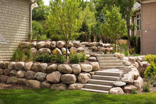 A stone wall with stairs leading up to a house.