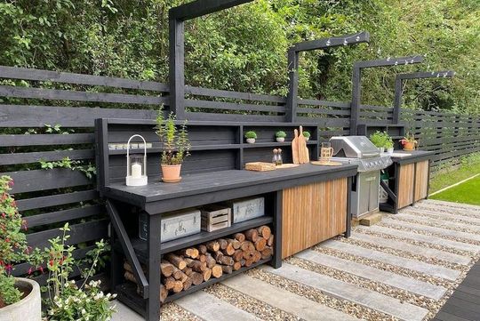 A large outdoor kitchen with a grill , sink , and shelves.