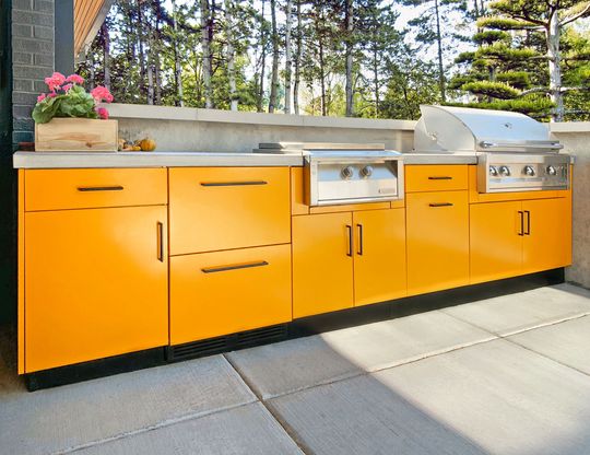 An outdoor kitchen with orange cabinets and a grill