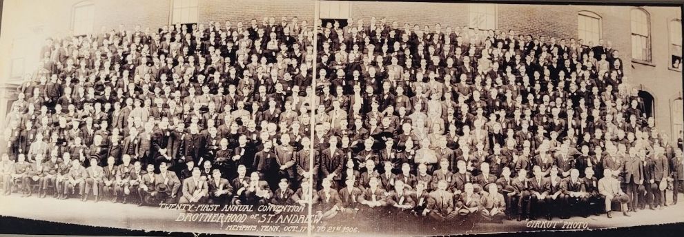 Large group photo of people seated indoors, looking at the camera. Black and white.