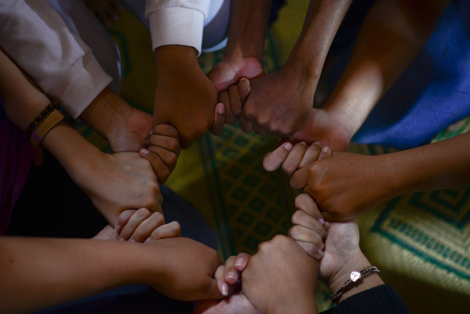 Hands clasped in a circle, diverse skin tones, emphasizing unity and connection.