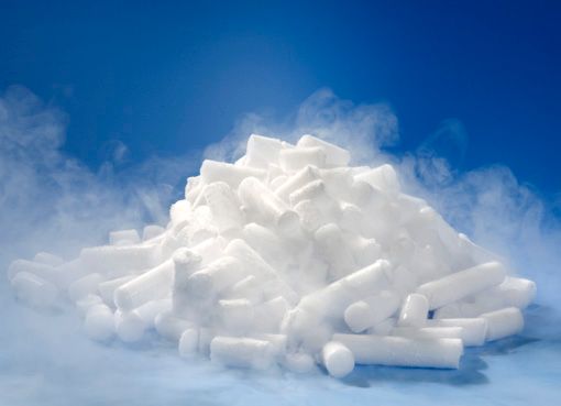 A pile of dry ice on a blue surface with smoke coming out of it.