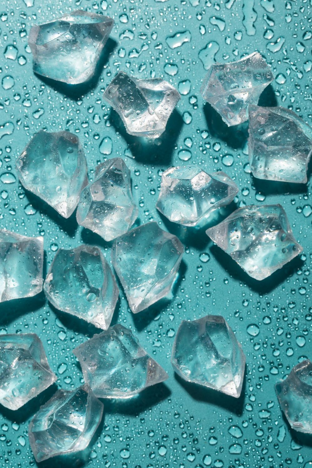 Ice cubes on a blue surface with water drops.