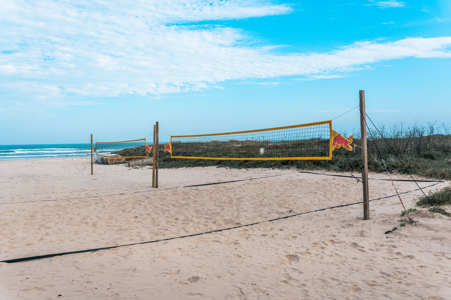 Beach volleyball net on a sandy beach under a blue sky.