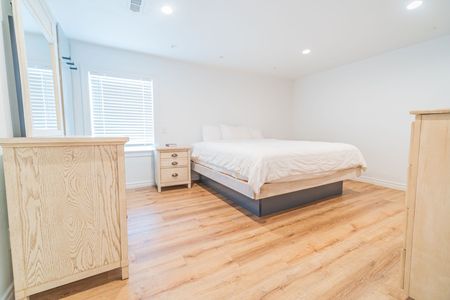 Bedroom with hardwood floors, a bed, two dressers, a nightstand, and a window.