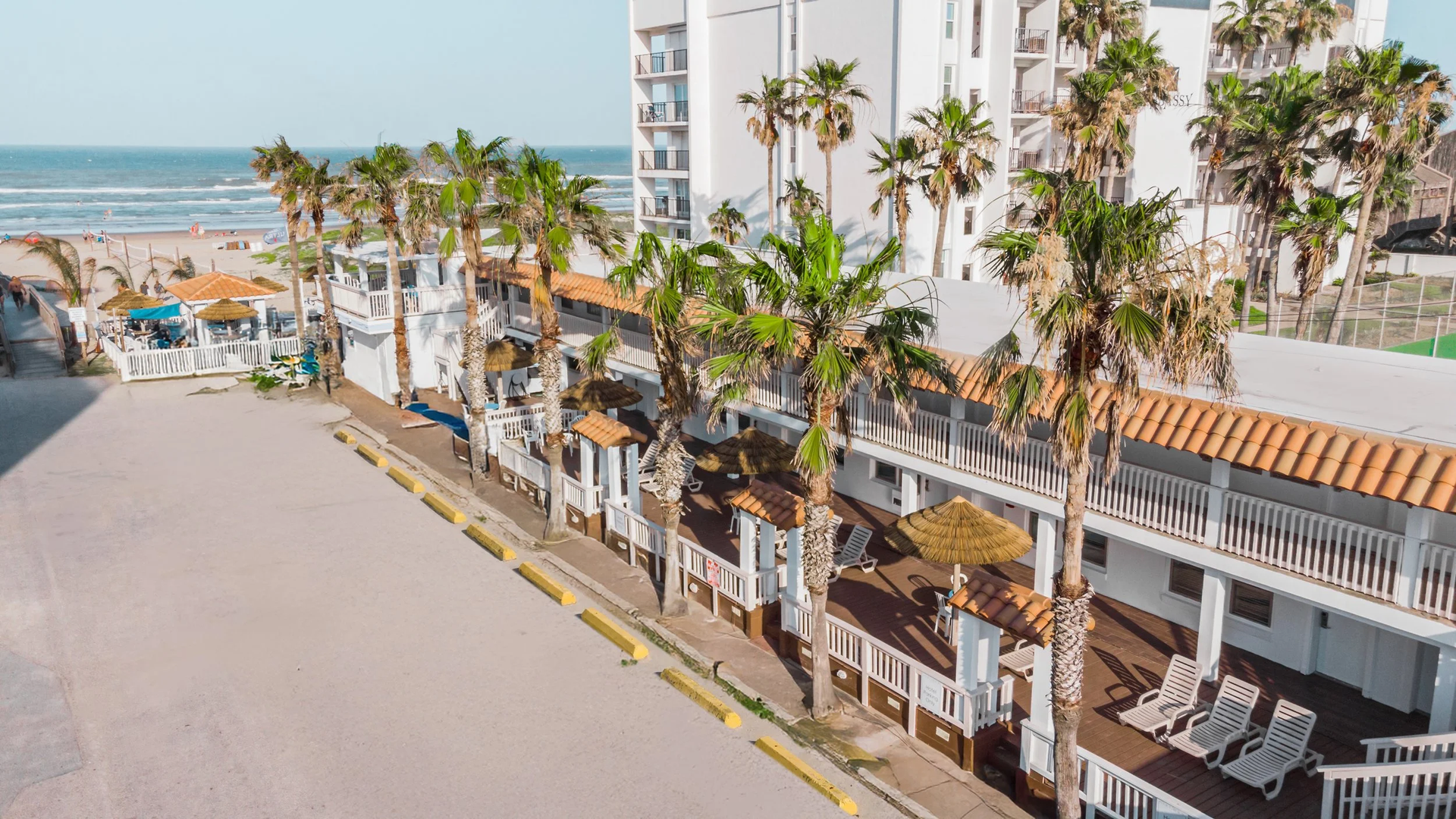 Sign for Coco Beach Hotel, white building, palm trees, blue sign.