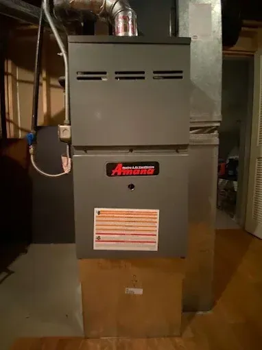 A gray Amana furnace in a basement setting.
