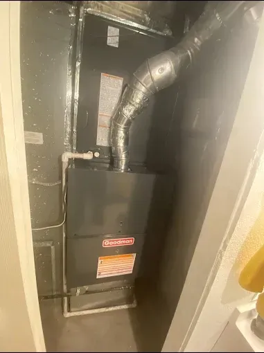 Furnace in a utility closet with silver ductwork.