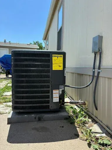 Outdoor air conditioning unit attached to a light-colored building.