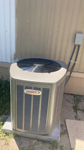 Lennox air conditioning unit outside a building, with a fan and a metal casing.