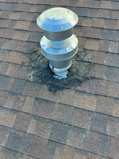 Roof vent on a shingle roof with black sealant surrounding the base.